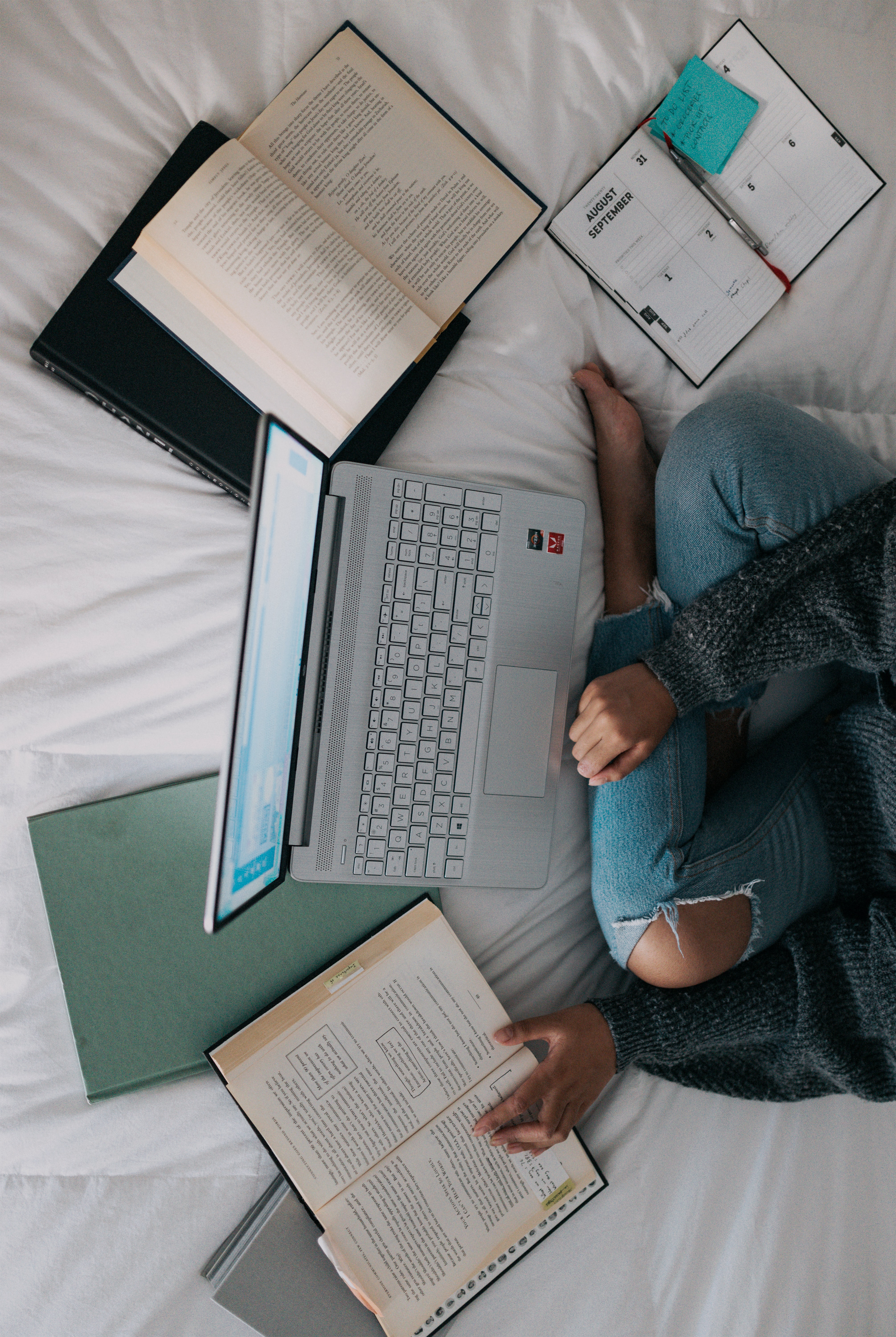 Open books spread around someone on a laptop.